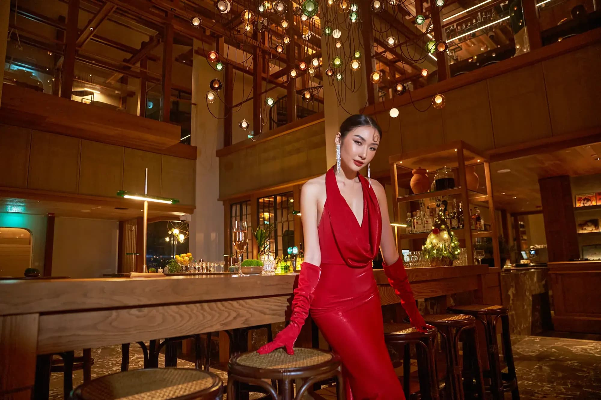Người mẫu váy đỏ trong quầy bar ánh đèn ấm, bộ ảnh thời trang XITA x Hoiana